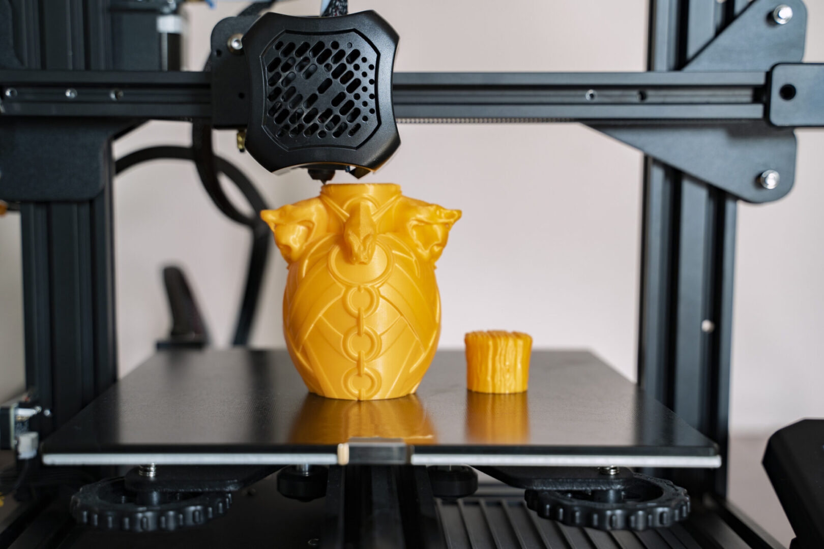 3D printer creating intricate yellow object.