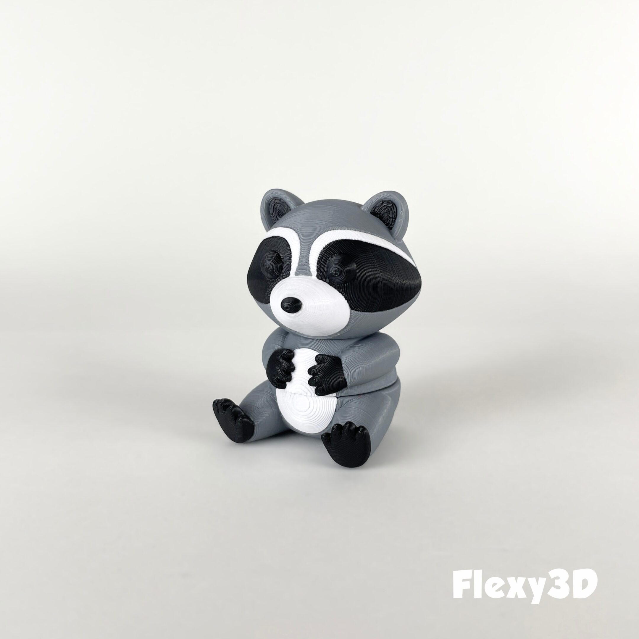 A cute, small raccoon figurine sitting on a white surface.