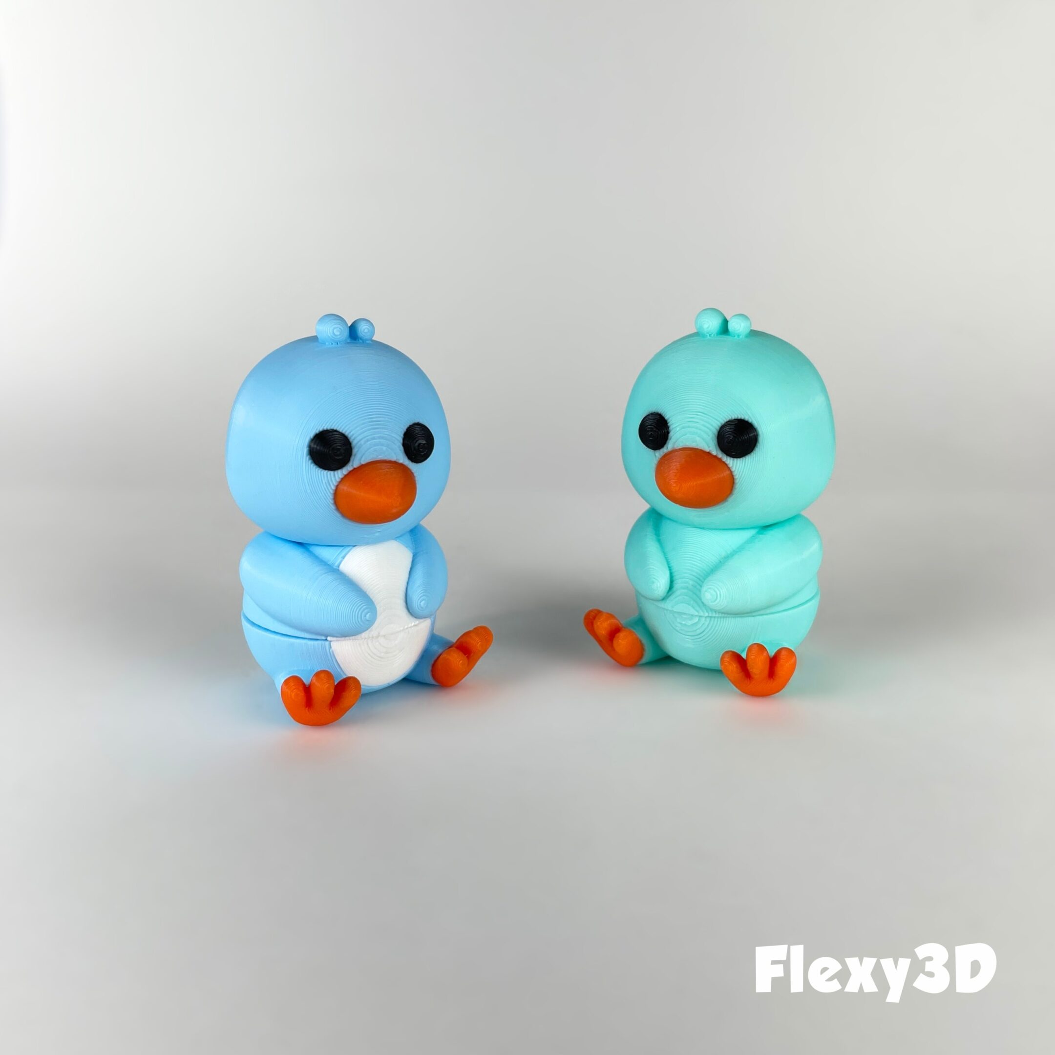 Two cute blue bird figurines with orange feet and beaks.
