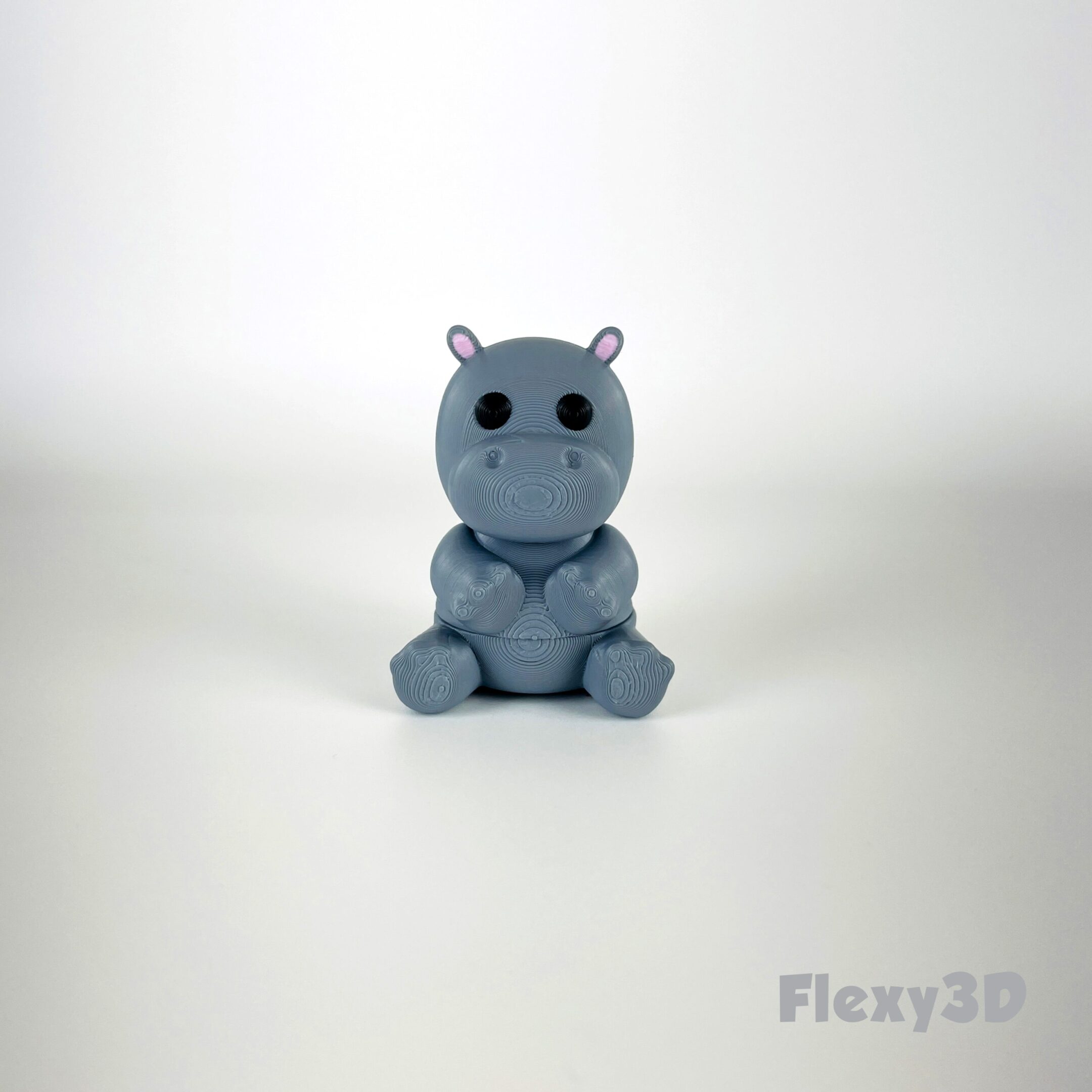 A small, cute blue hippo toy on a white surface.