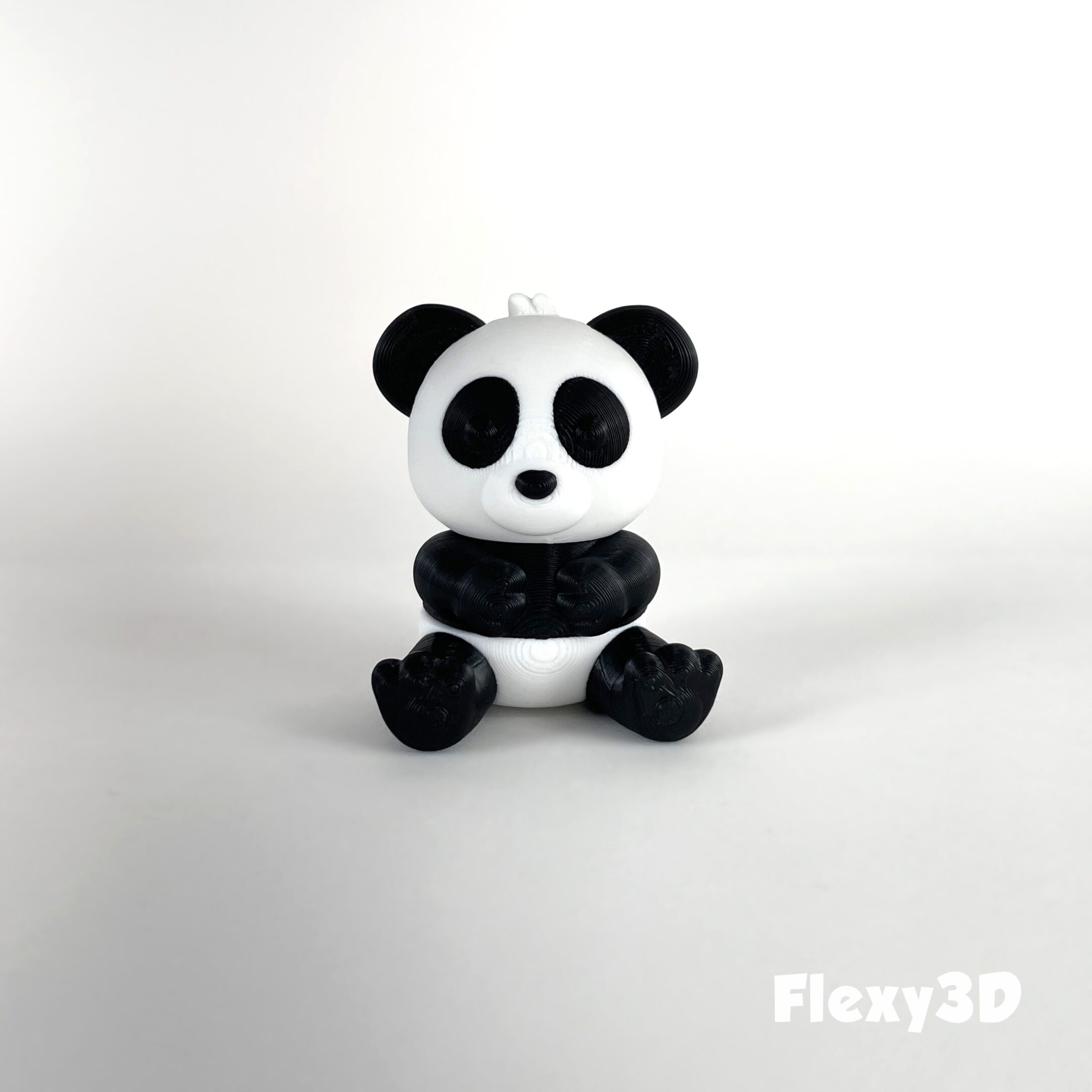 A cute panda figurine sitting on a white surface.