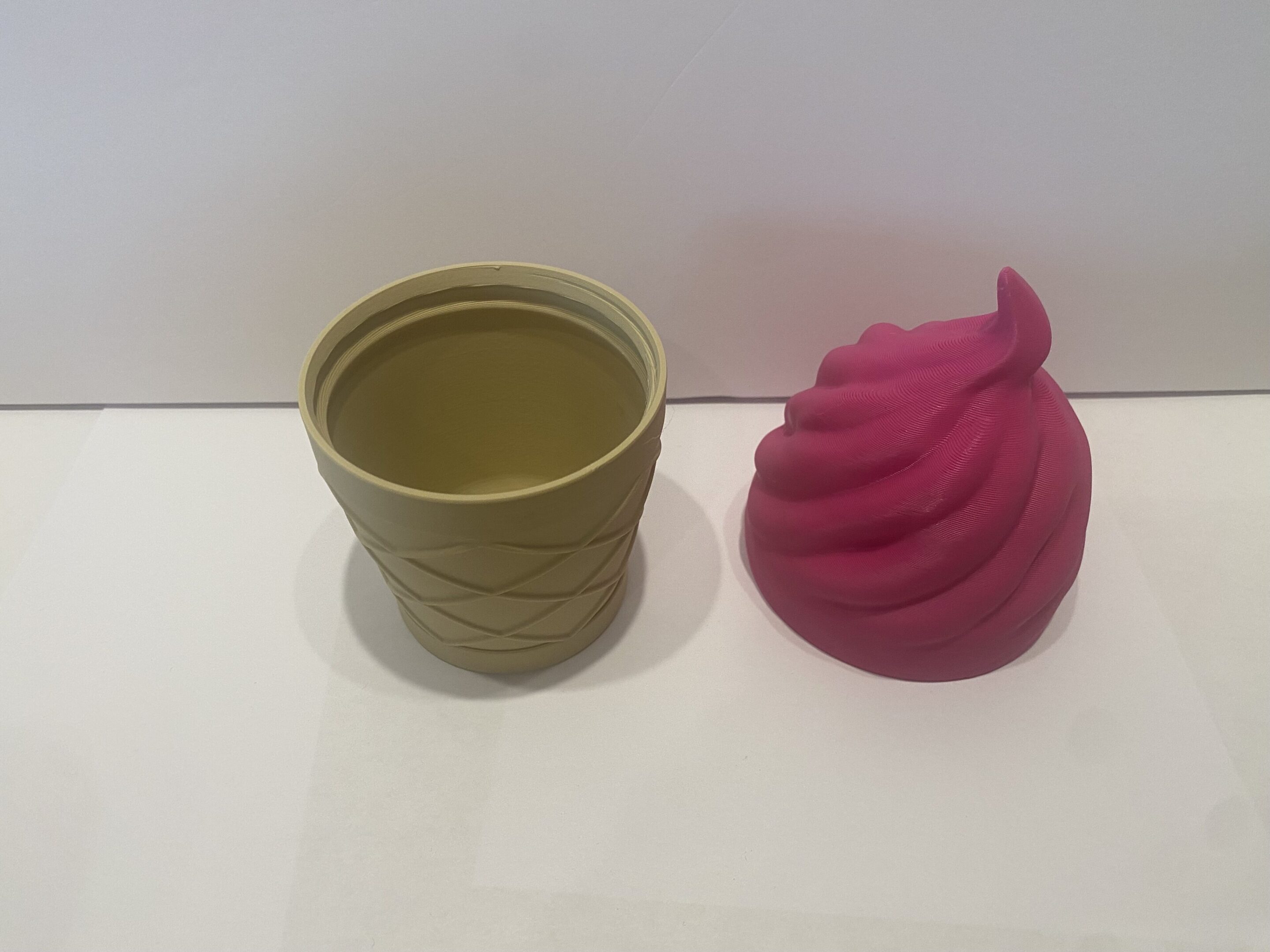 A beige cup and a pink swirl-shaped object on a white surface.
