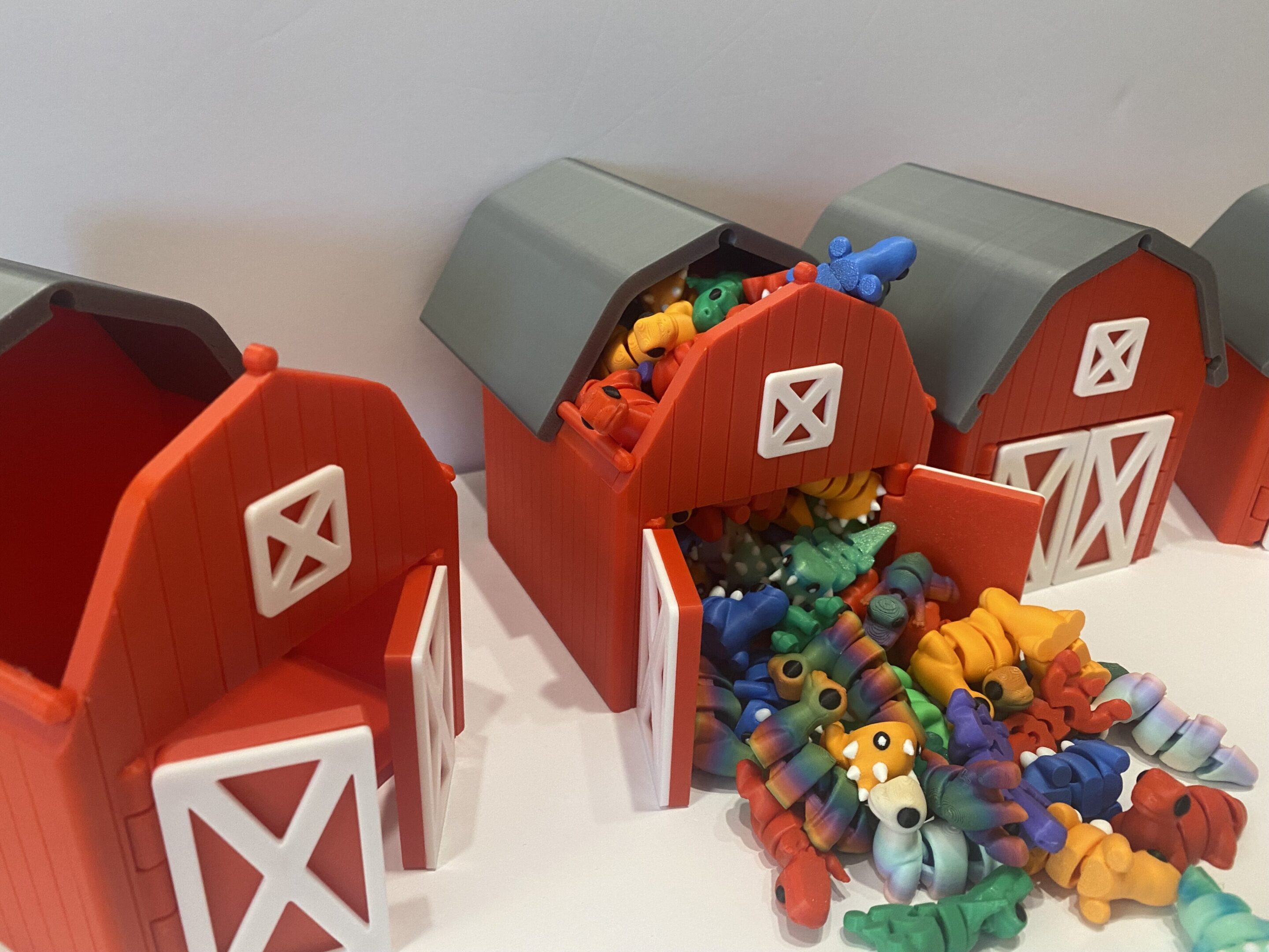 Three toy barns with colorful toy animals scattered around.