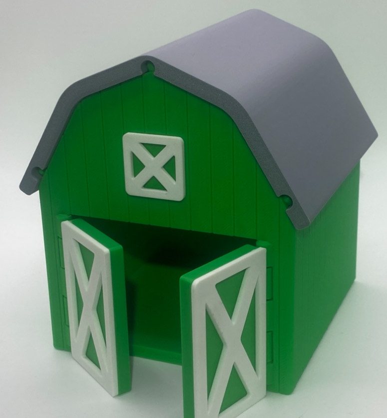 A small green toy barn with open double doors and a gray roof.