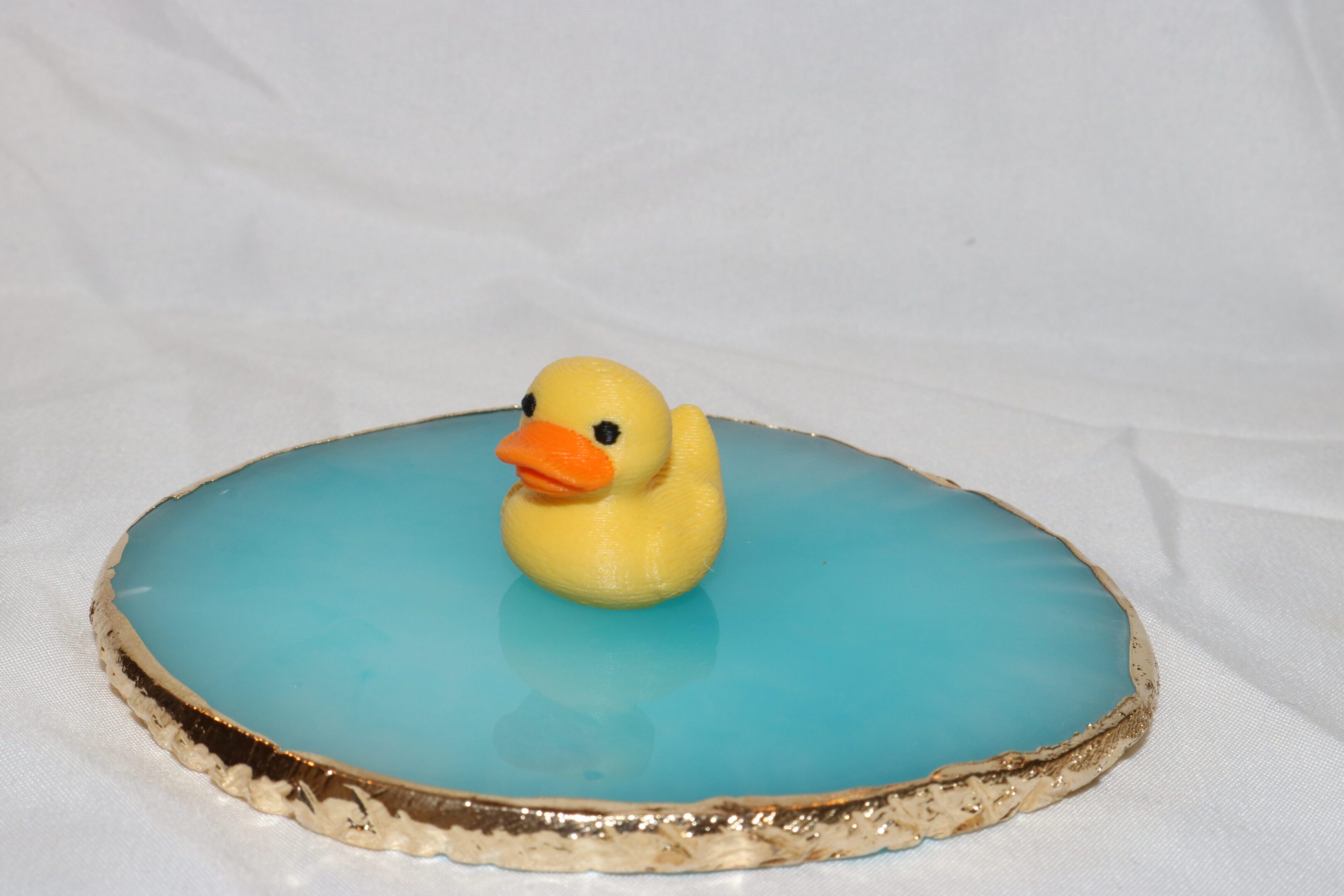 A yellow rubber duck floats on blue water atop a wooden surface.