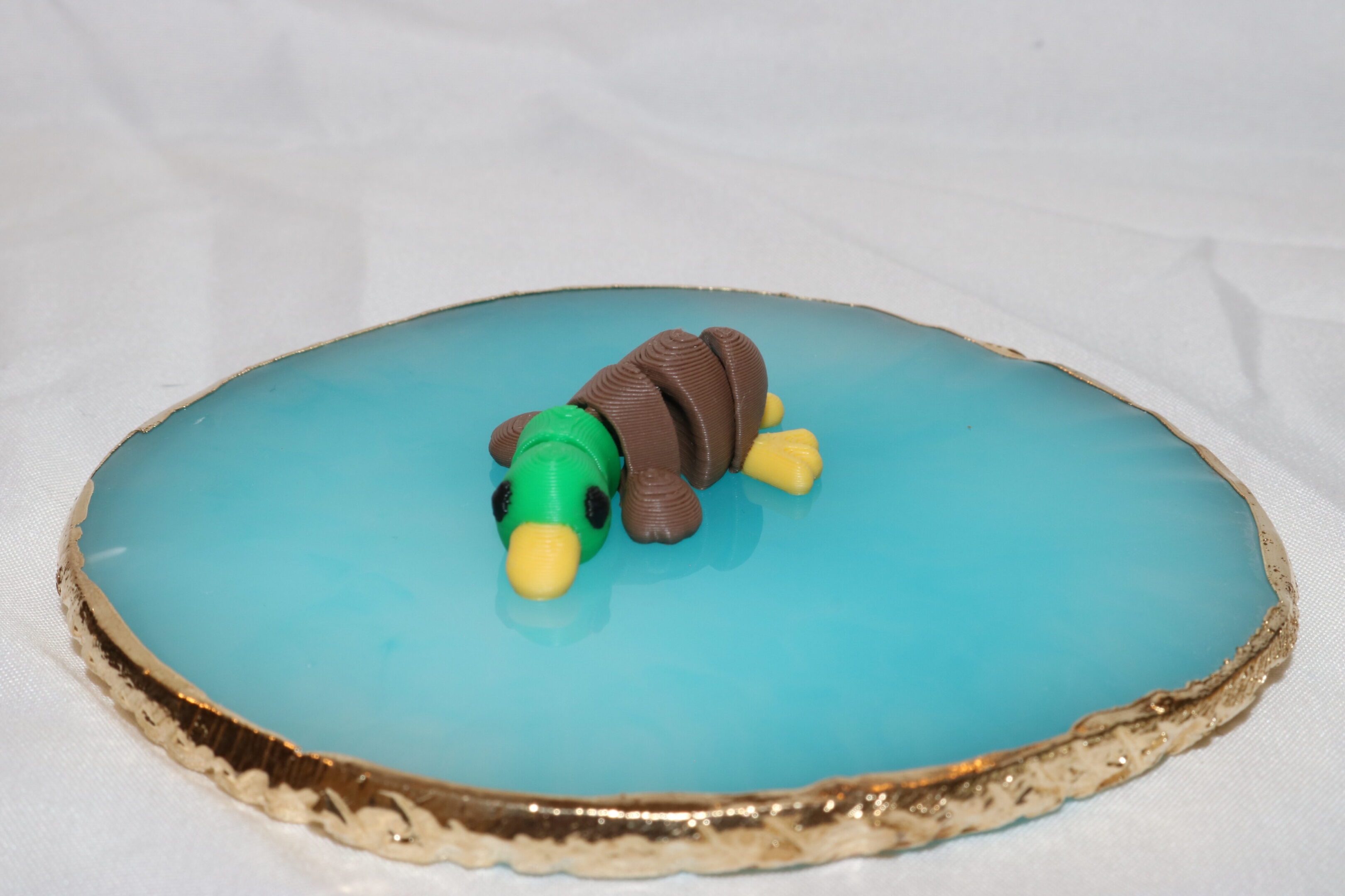A duck-shaped cake with blue icing and detailed fondant features.
