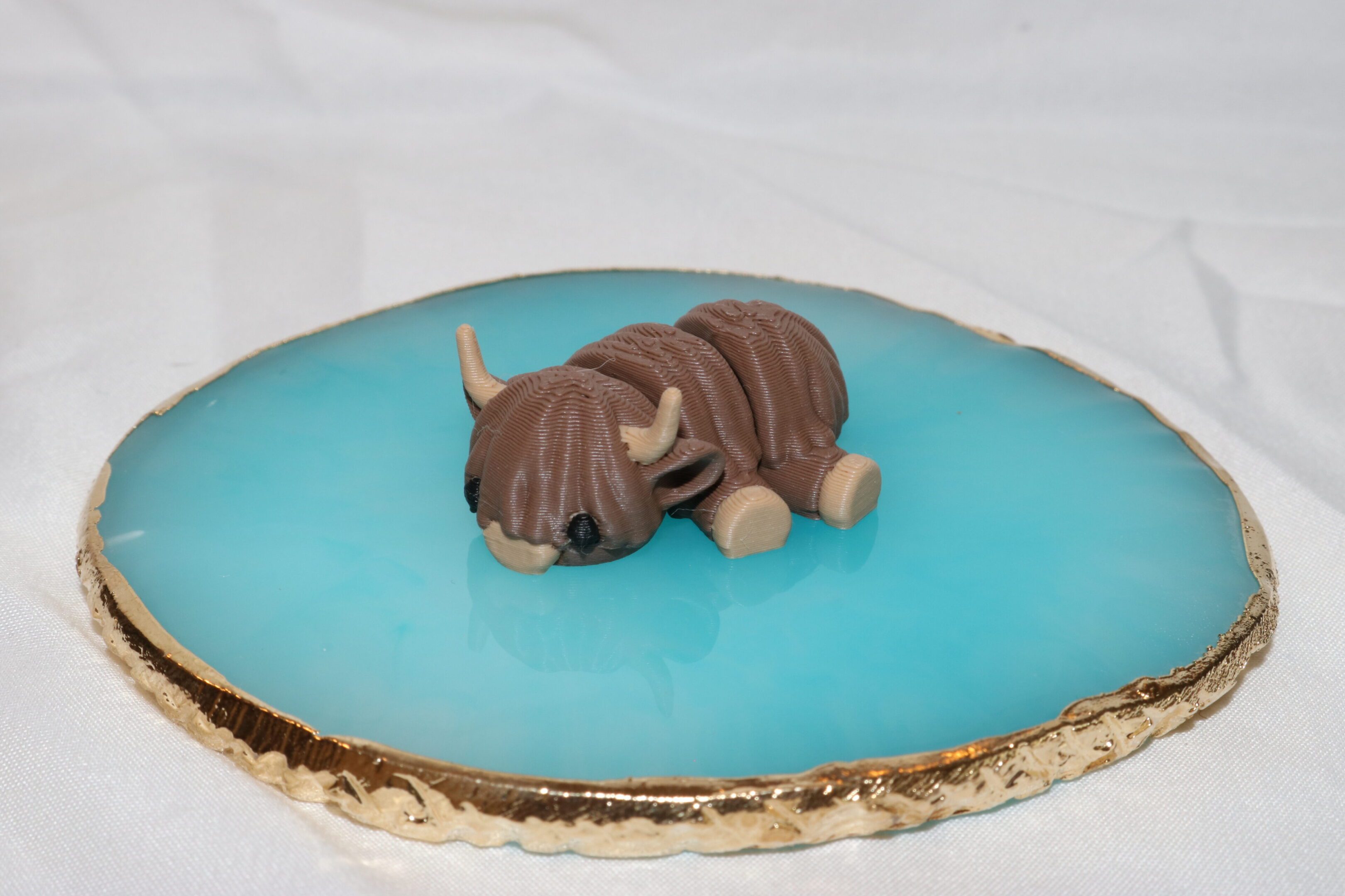 A small, sleeping dog figurine on a blue glazed surface.