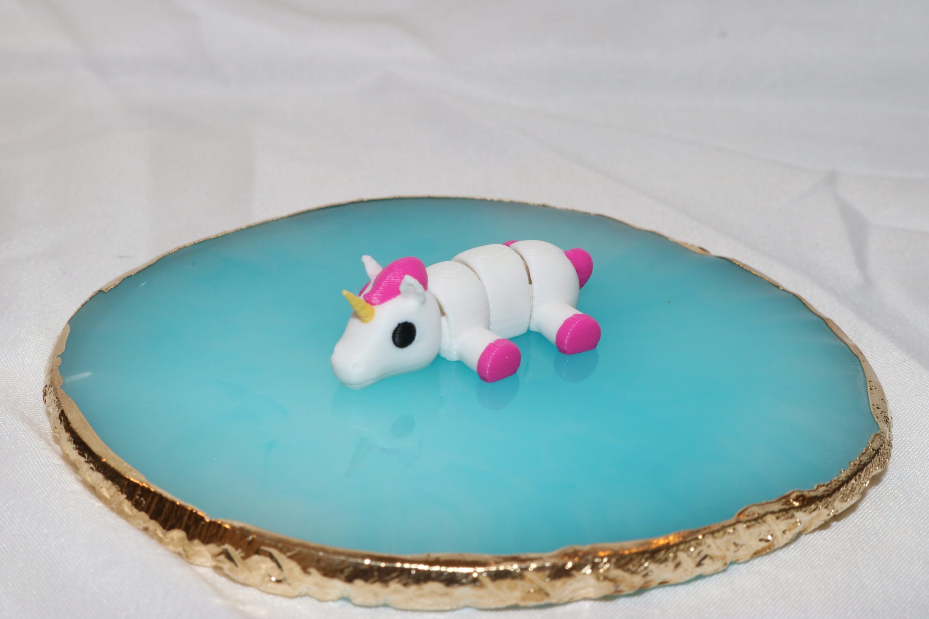A cake topped with a fondant unicorn figure on blue icing.