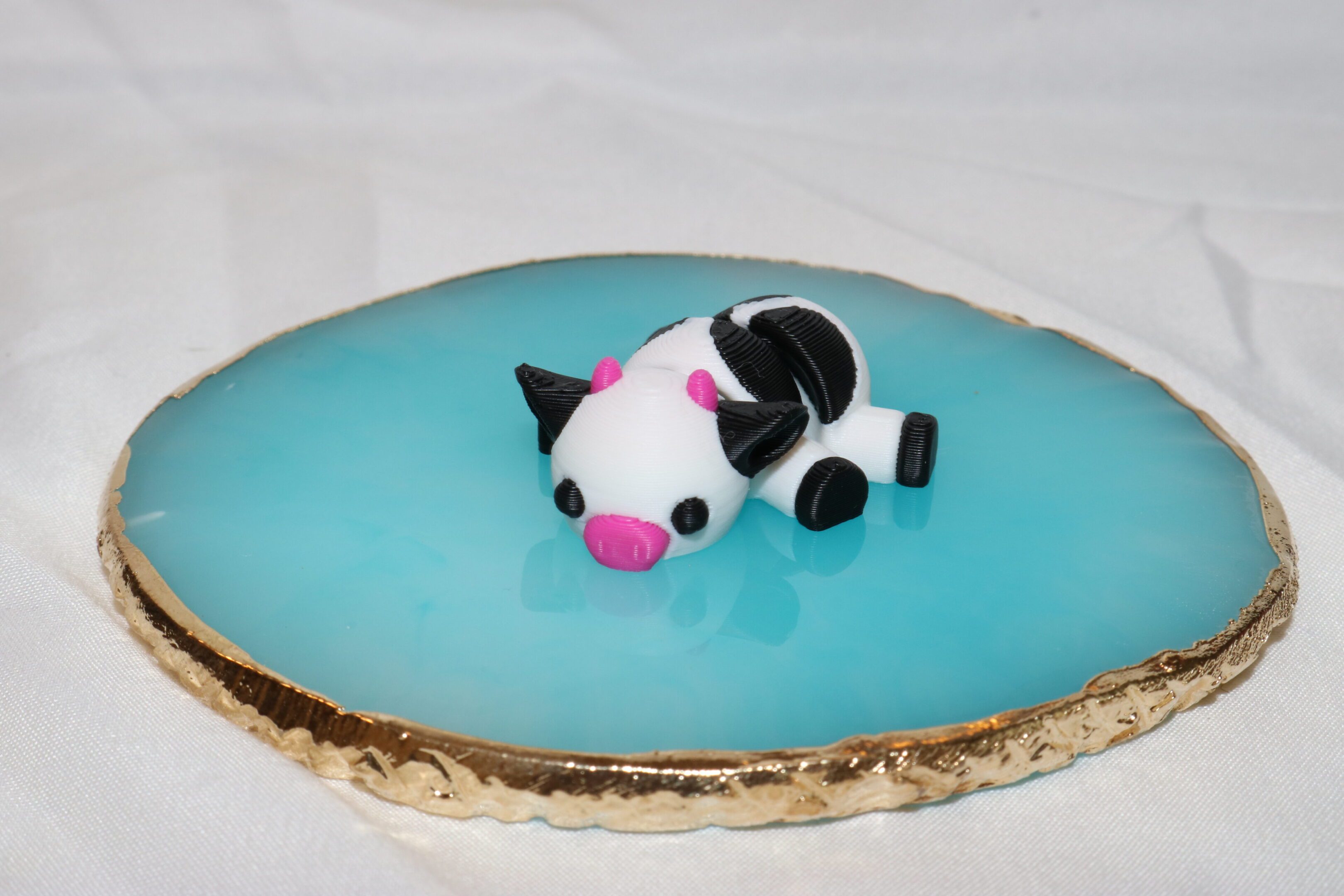 A small fondant cow floating on blue gelatin resembling water.