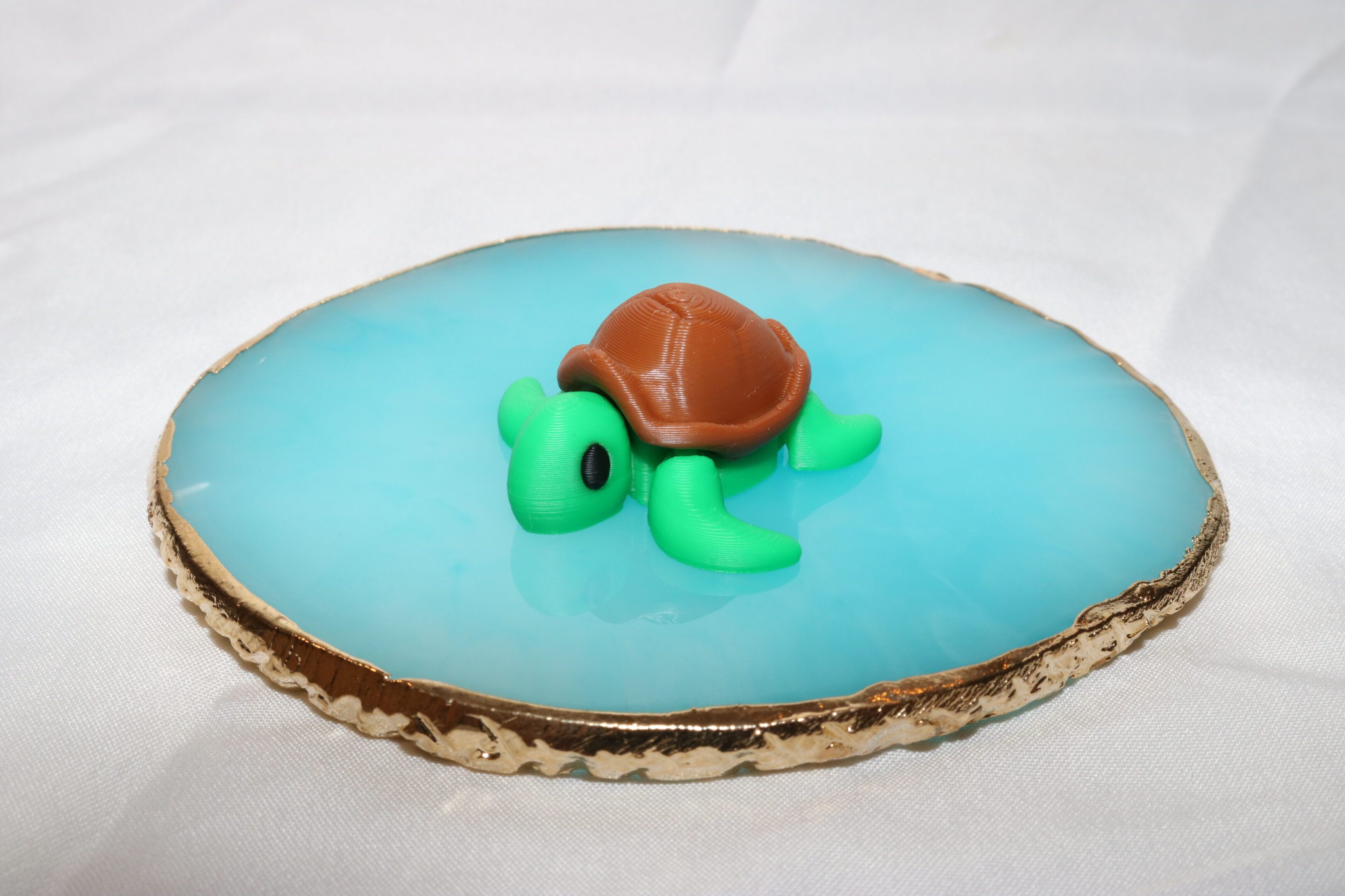 A small turtle figurine on a blue surface with a wooden edge.