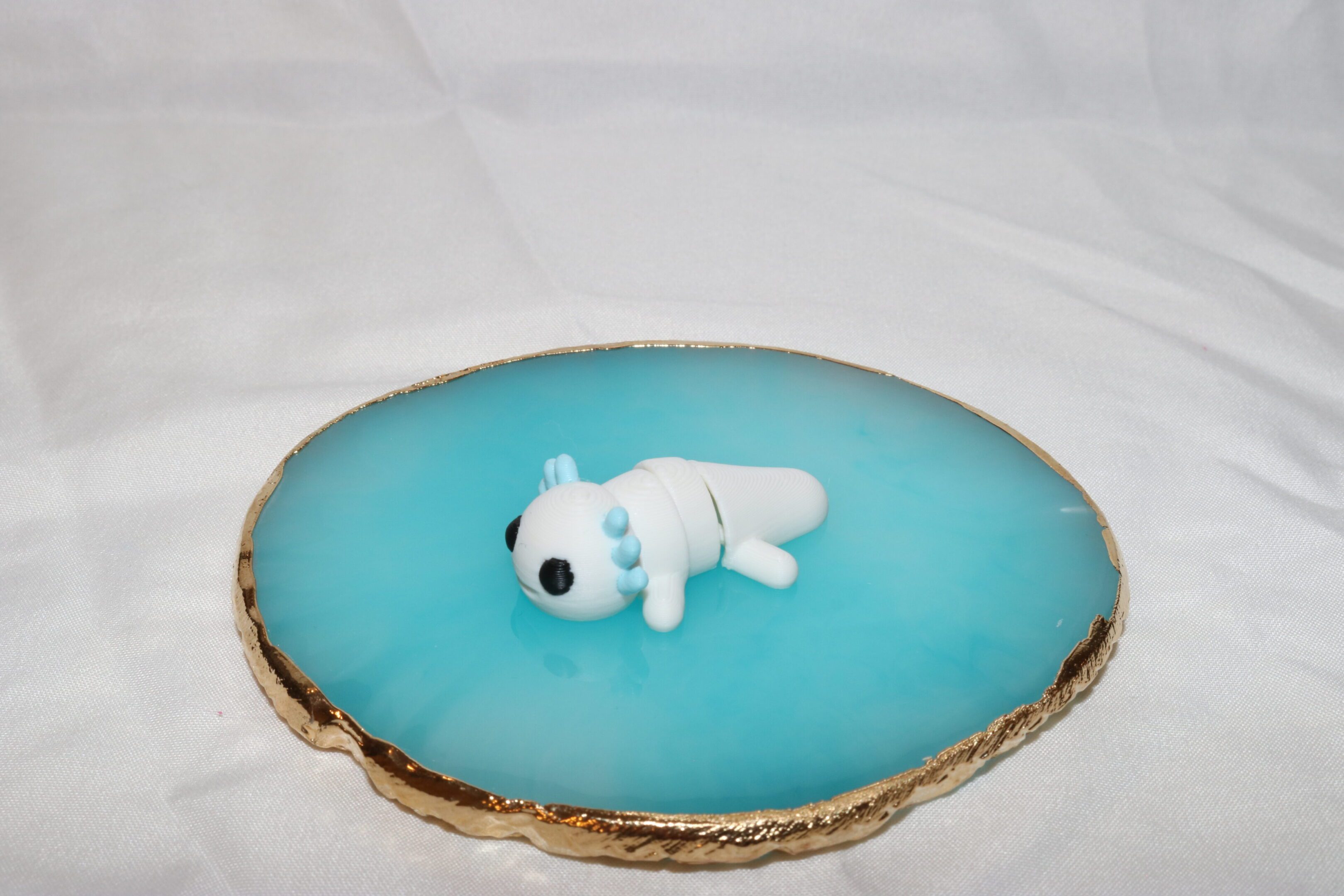 A small white polar bear figurine on a blue resin surface with a wooden edge.