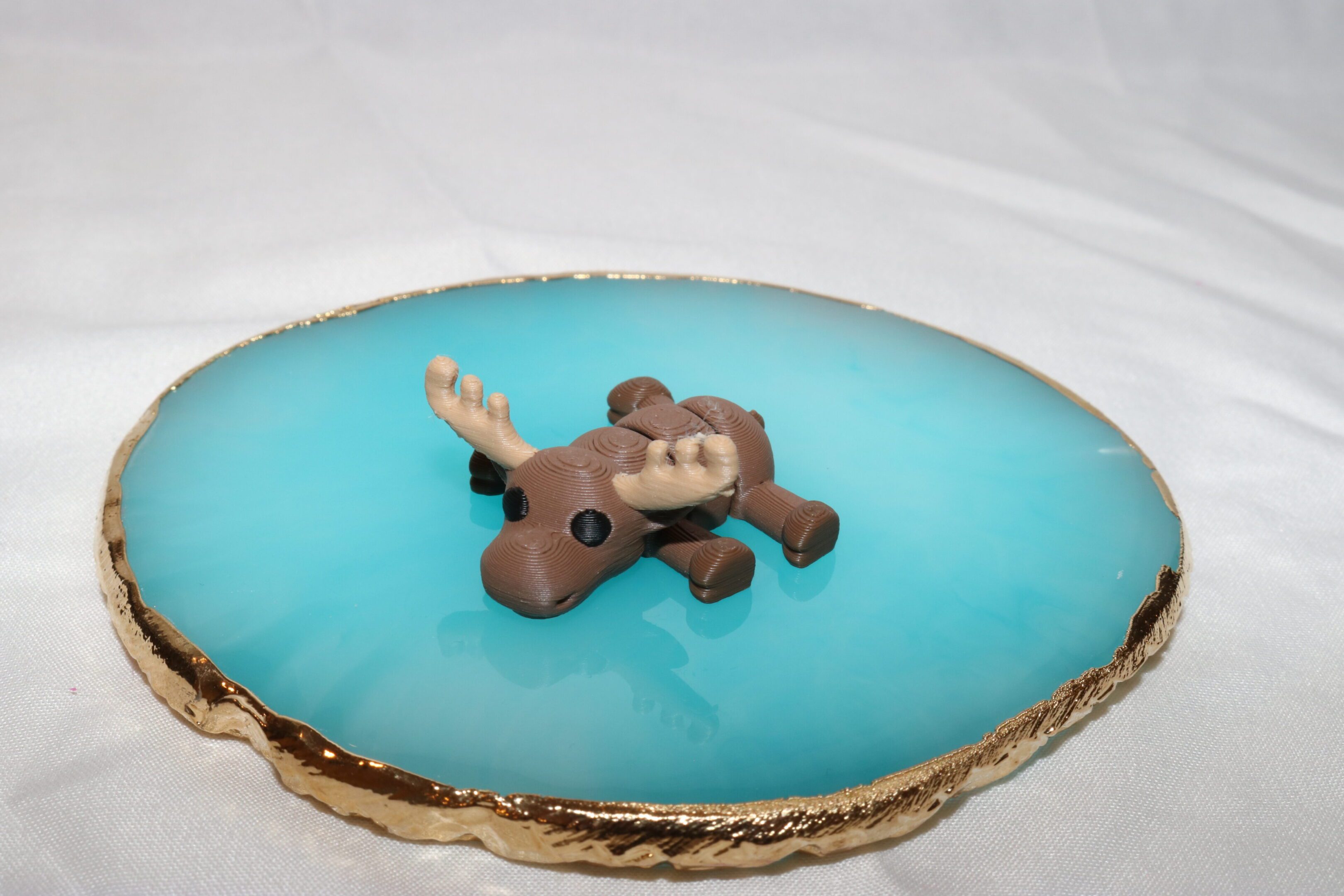 A cute reindeer figurine resting on blue resin with a geode edge.