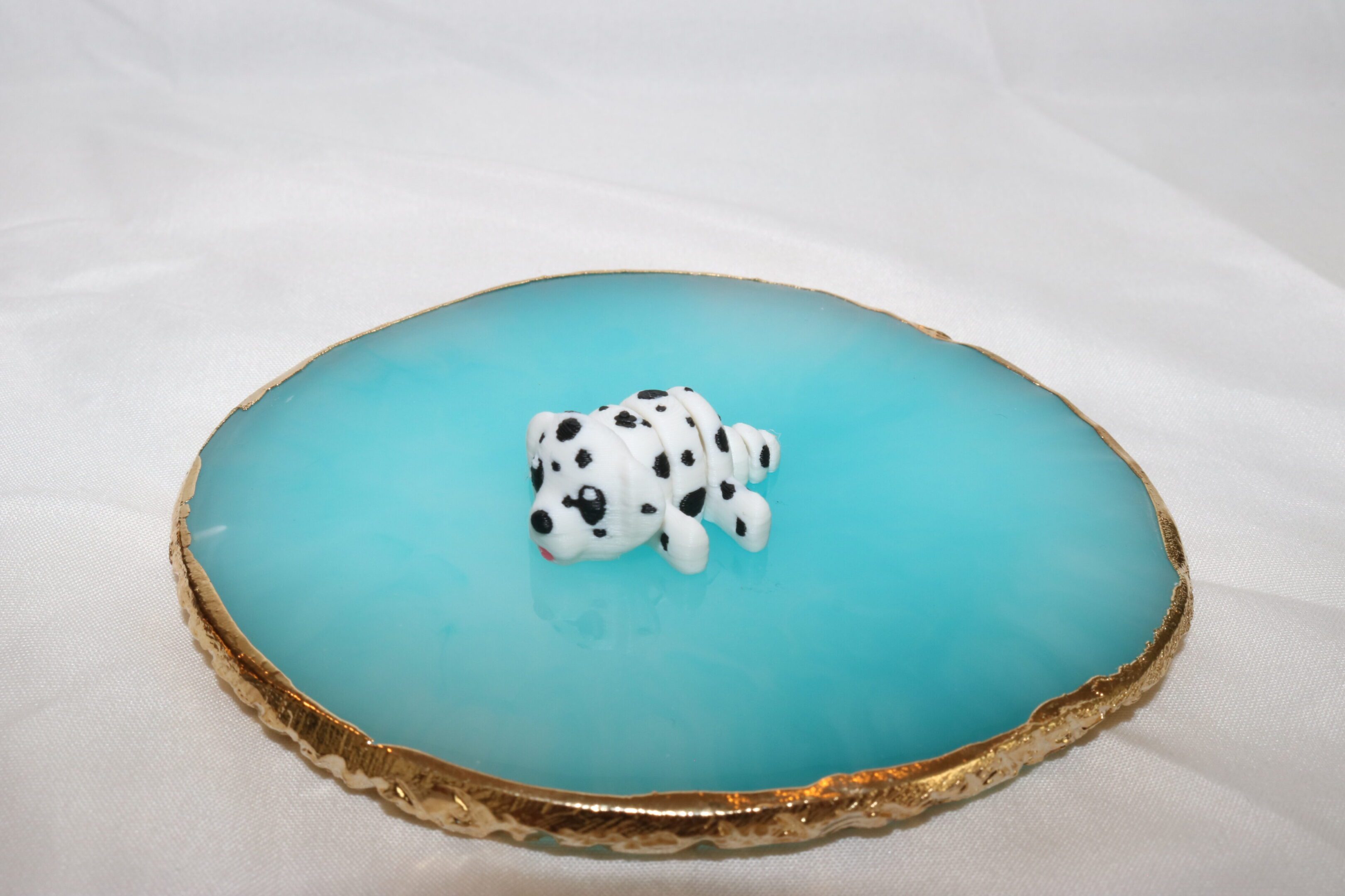 A small cow figurine on a blue agate slice with a white background.