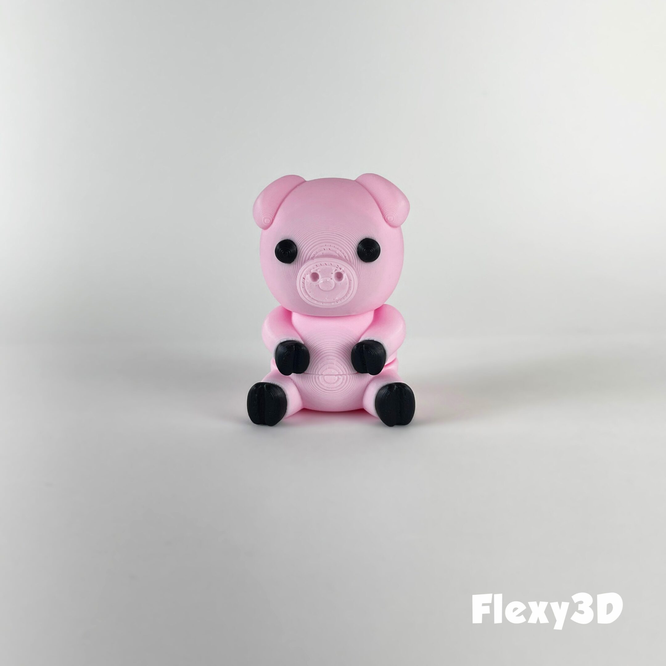 A pink teddy bear toy sitting on a white surface.