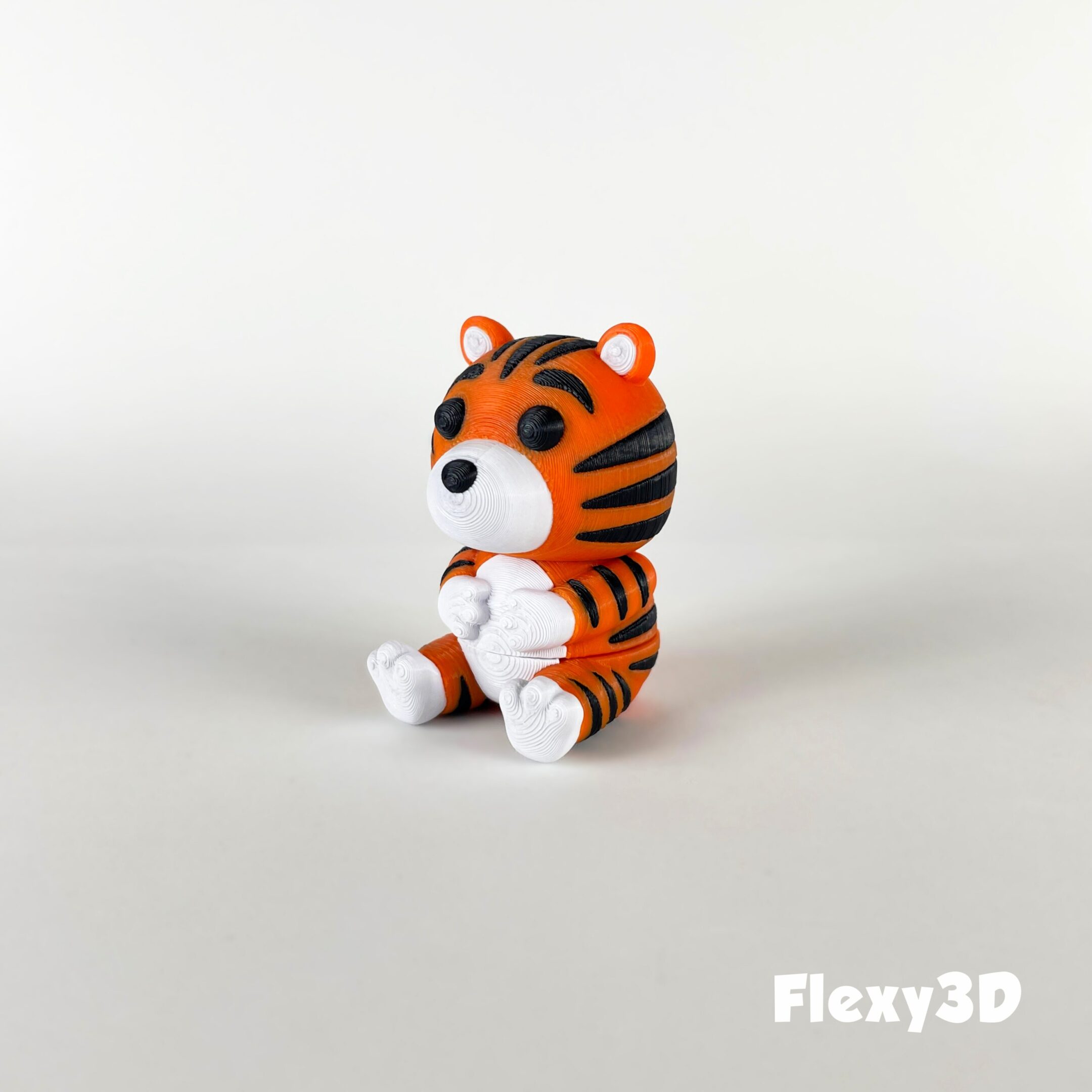 A small, cute tiger figurine sitting on a white surface.