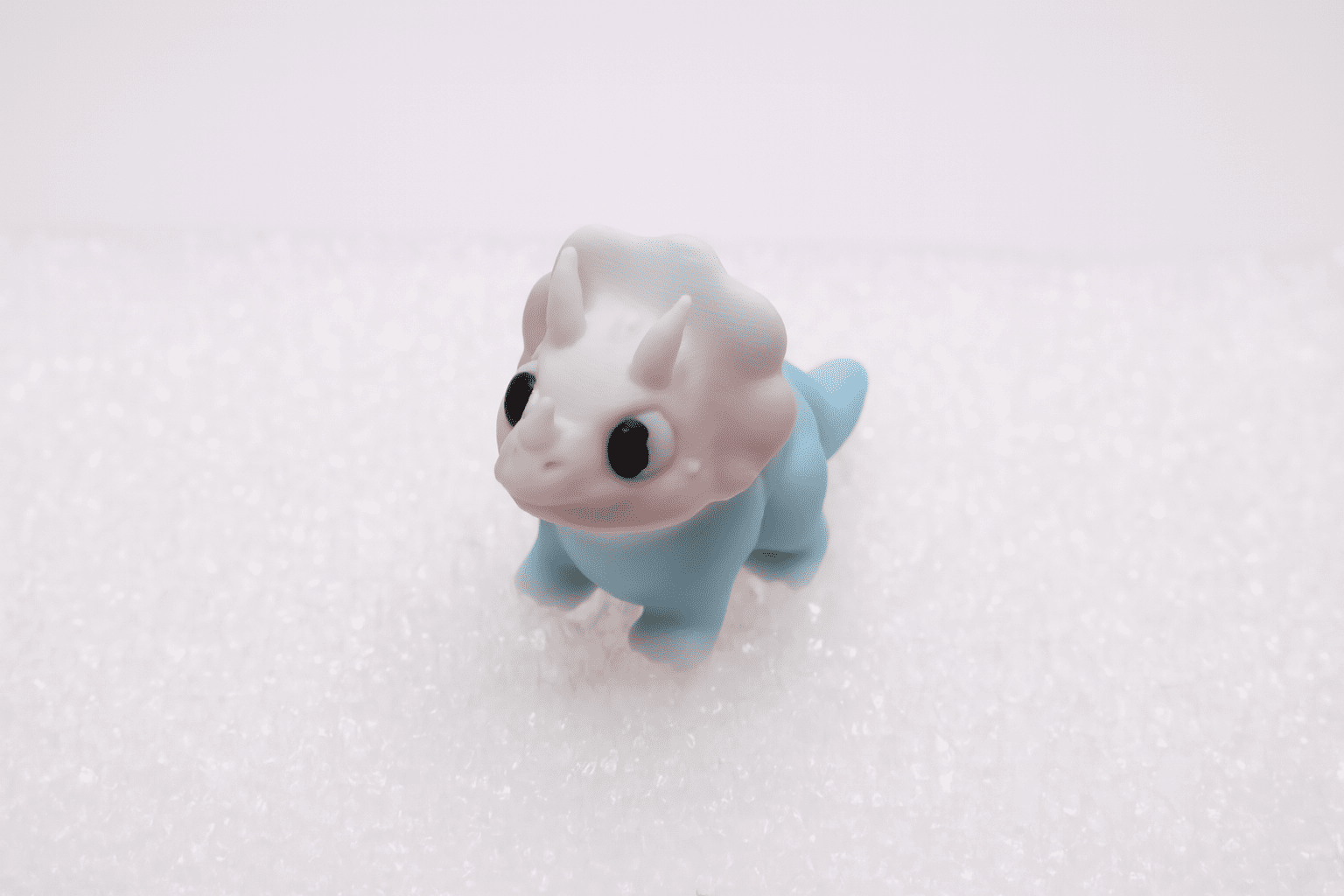 A small, cute toy dragon with big eyes and blue wings.
