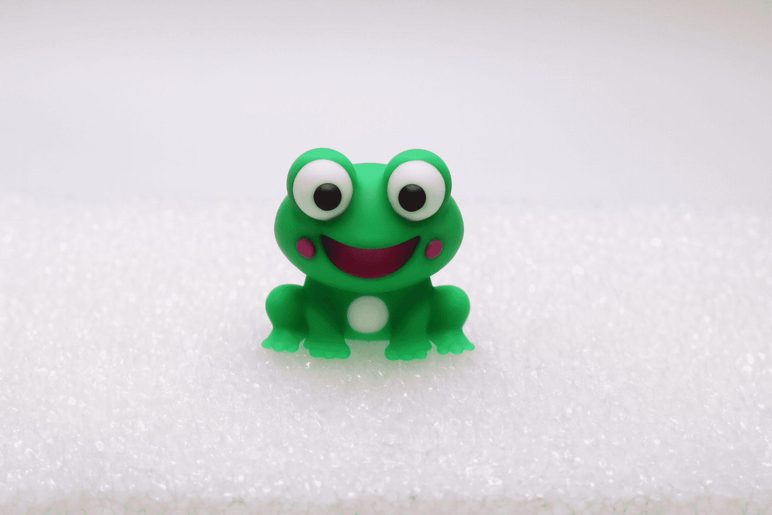 A cute green frog toy with big eyes and a smile.