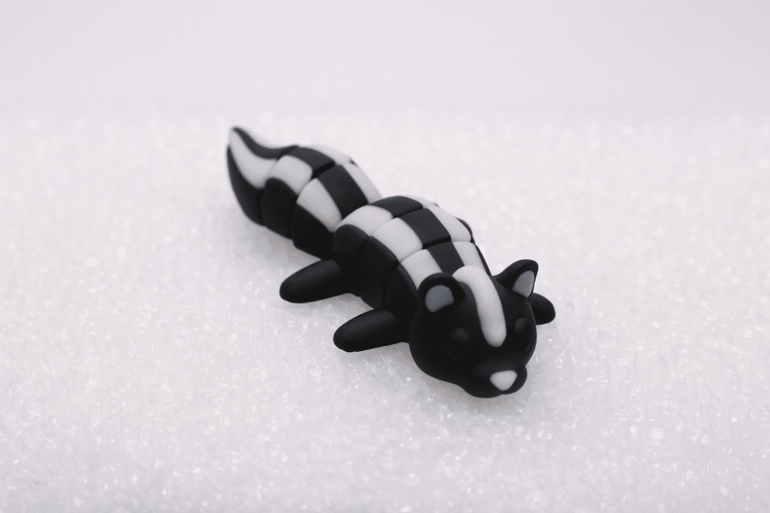 A small black and white salamander figurine on a white surface.