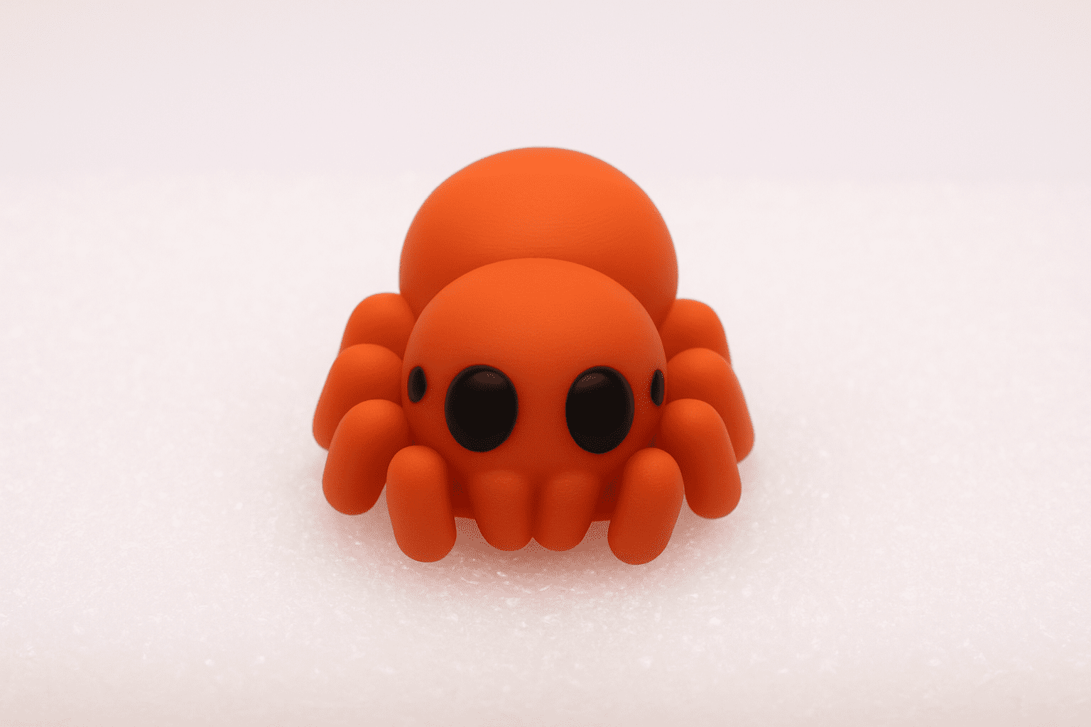 A cute, small orange spider figurine with big black eyes.
